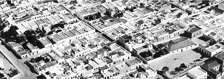 Fotografia aérea antiga a preto e branco do casario da Fuseta, com ruas ortogonais, quarteirões regulares e açoteias.