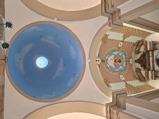 Vista em contrapicado da cúpula pintada de azul com nuvens e óculo central, junto ao teto decorado da capela-mor e ao topo do retábulo